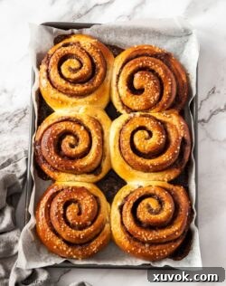 6 large cinnamon buns on a baking tray.
