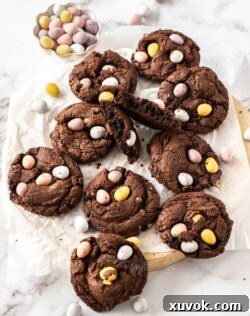 A batch of chocolate cookies on a wooden platter with mini eggs around.