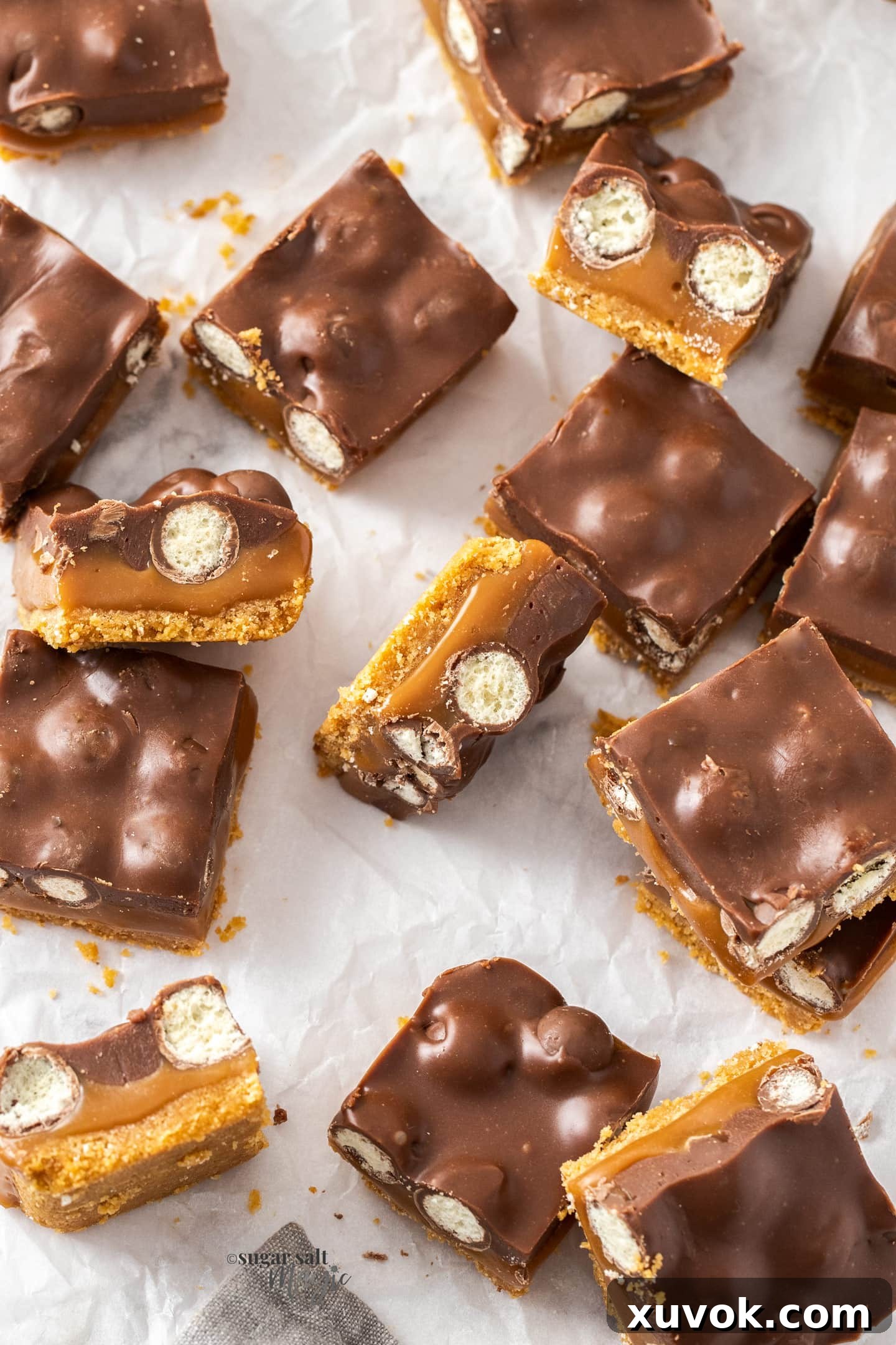Close-up of a stack of Caramel Malteser Slices, highlighting the glossy chocolate topping and visible Malteser crunch.