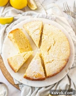 Top down view of a lemon ricotta cake cut into slices on a white platter.