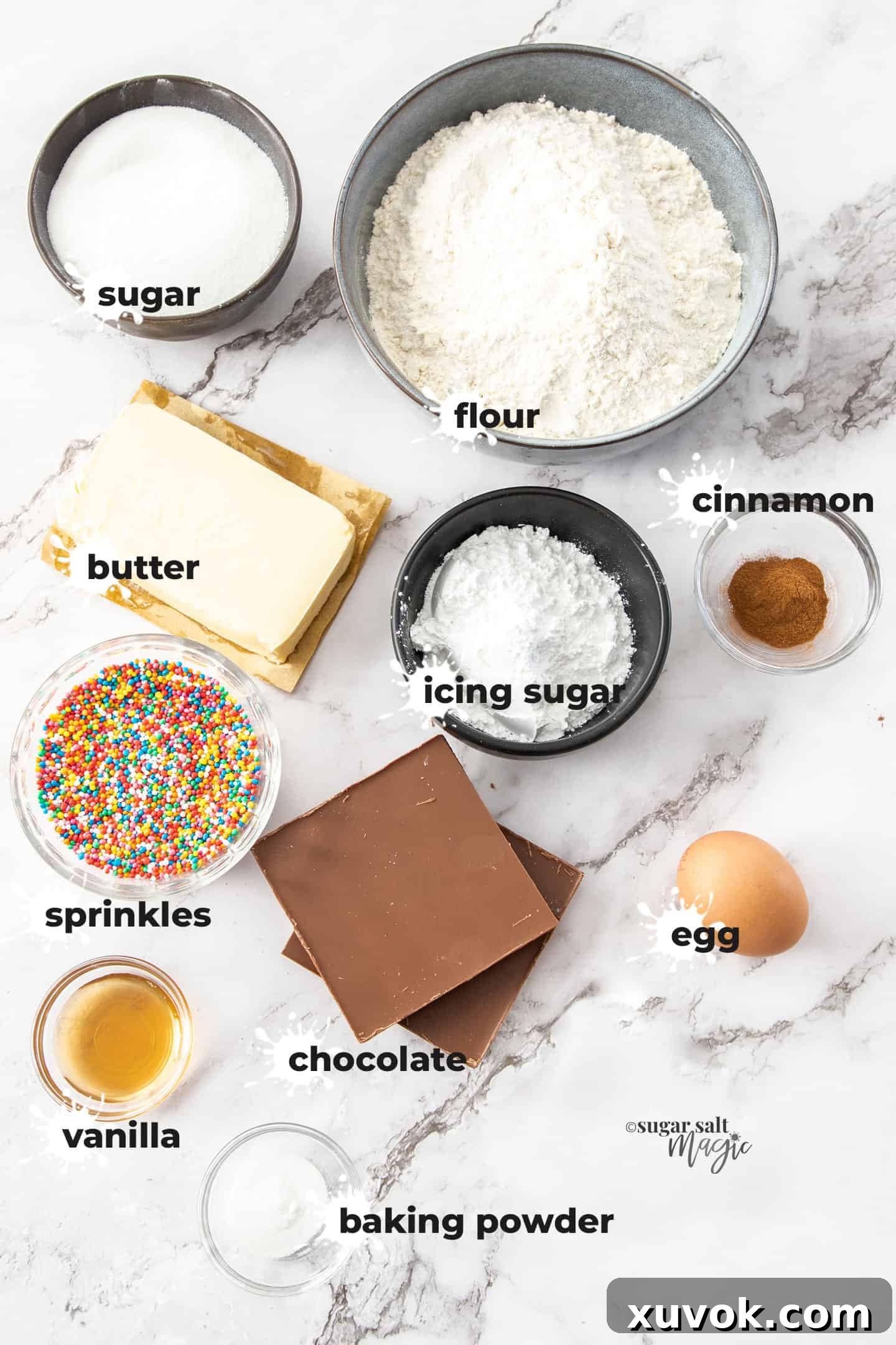 Key ingredients for baking cinnamon sugar donut cookies laid out in bowls on a white marble countertop, ready for preparation.