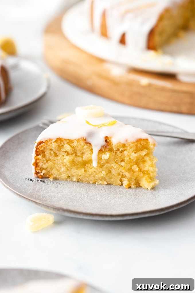 A vibrant slice of flourless lemon cake, adorned with a delicate white icing drizzle, rests on a sophisticated grey plate.