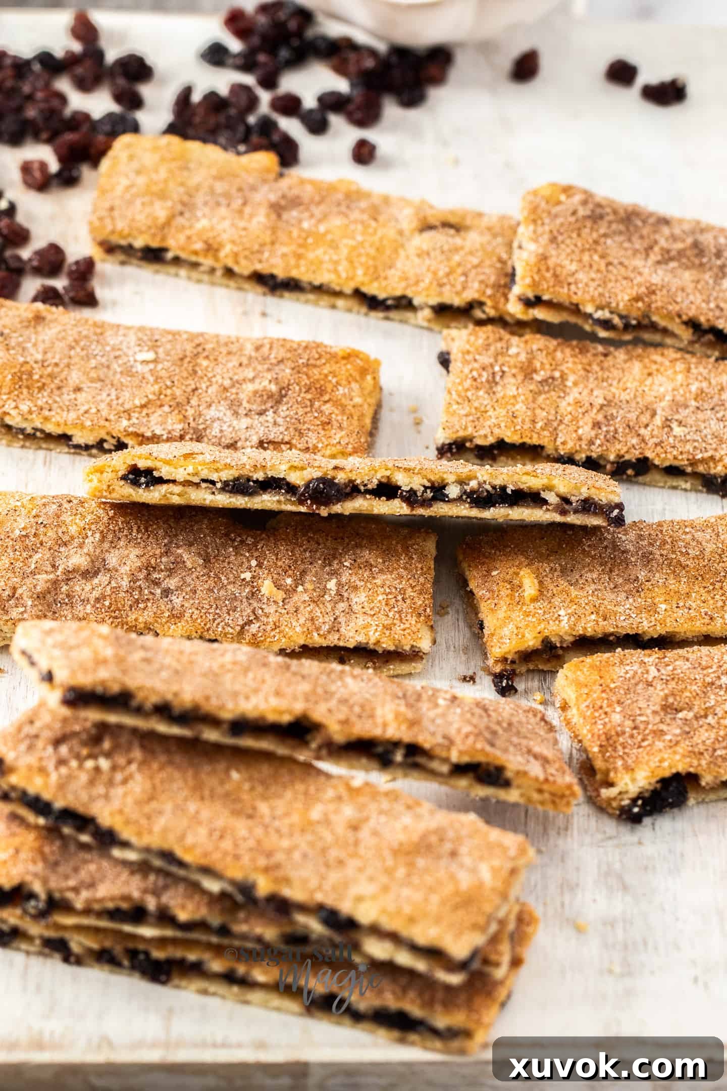 A generous batch of golden-brown rectangular Garibaldi biscuits, brimming with dried fruit, spread out beautifully on a white serving board, ready to be enjoyed.