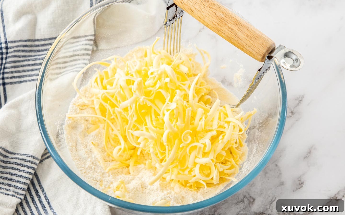 Cold, grated butter sitting on top of the flour and sugar mixture, ready to be blended for the biscuit dough.