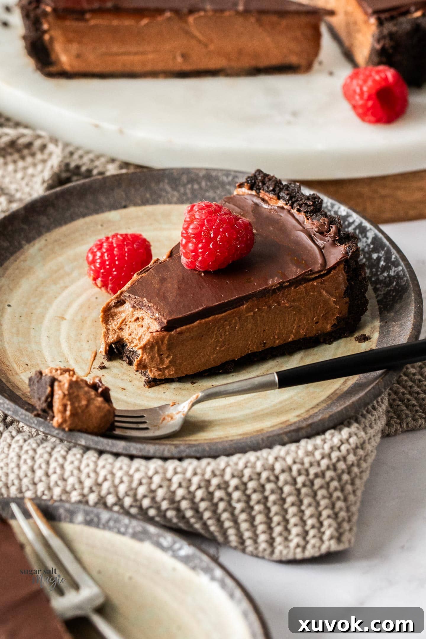 A slice of chocolate mousse tart on a dessert plate with a forkful cut away.