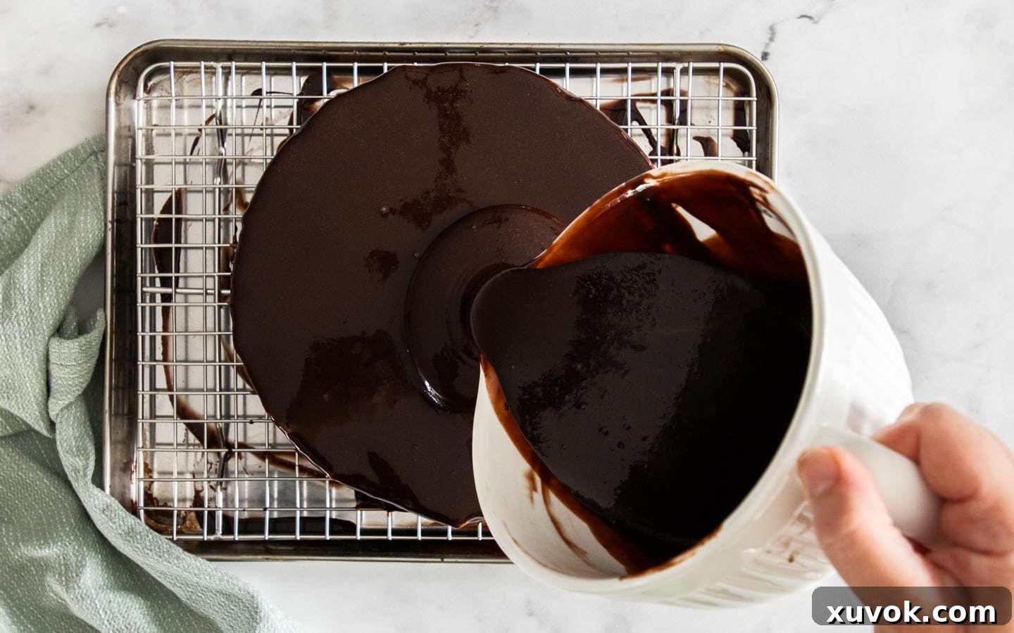 Pouring mirror glaze over the cake.