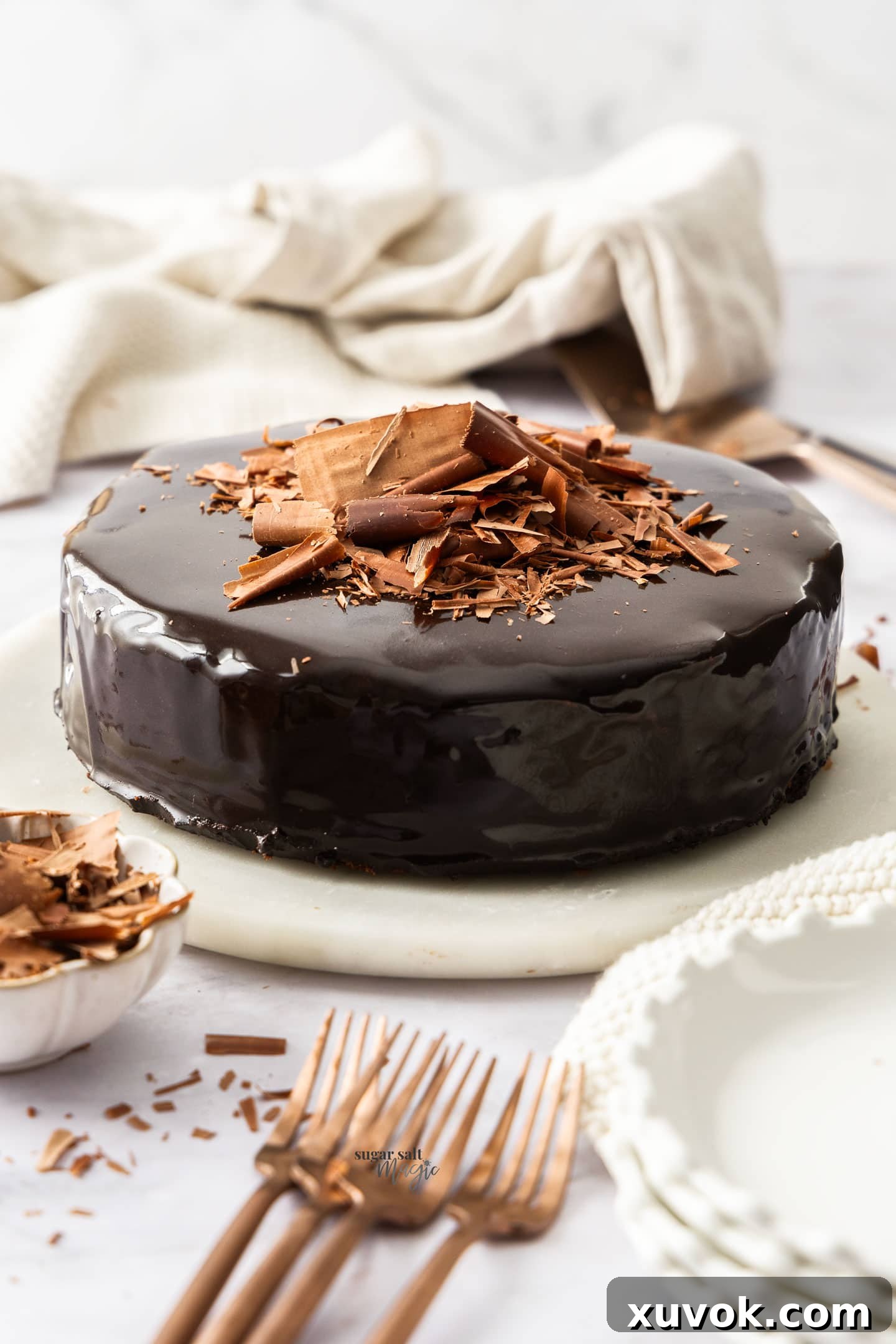 A chocolate cake with mirror glaze on a marble platter.