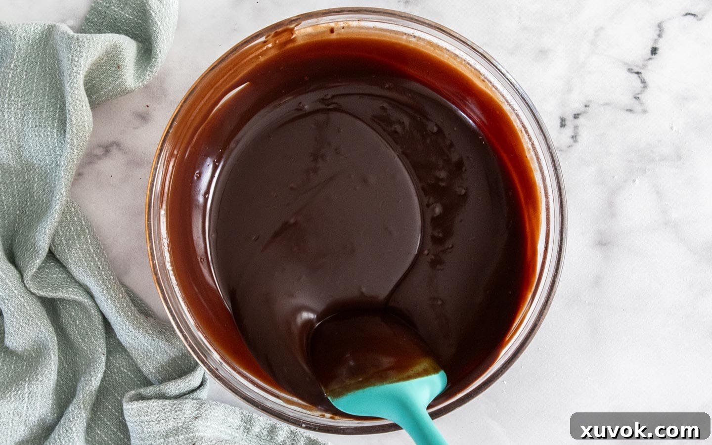 Chocolate ganache being stirred in a bowl.