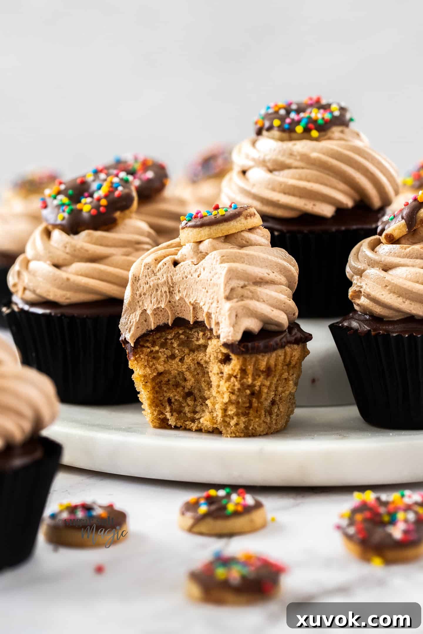 A delicious chocolate donut cupcake with a bite taken out, featuring a mini donut cookie on top, illustrating the perfect combination of flavors and textures.