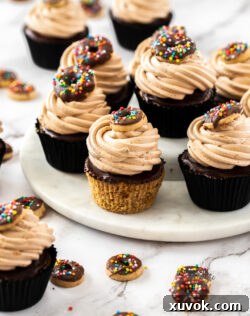 Seven fluffy chocolate donut cupcakes with swirls of frosting, presented on a pristine white marble platter.
