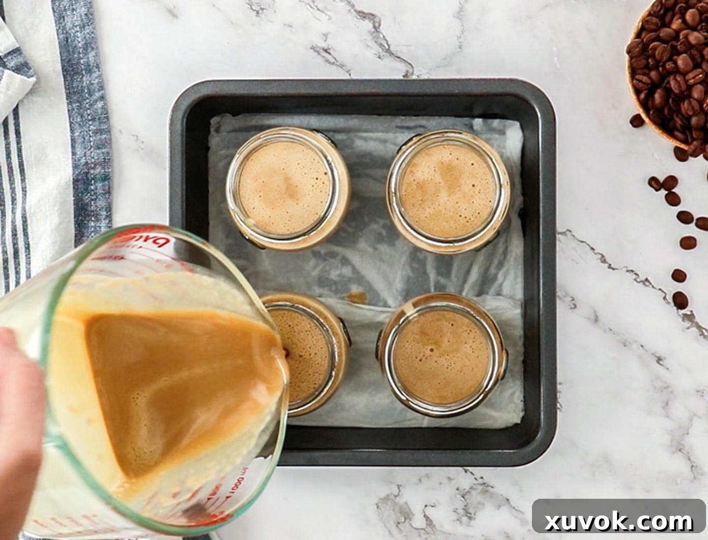 Pouring the coffee creme brulee custard into glass jars.