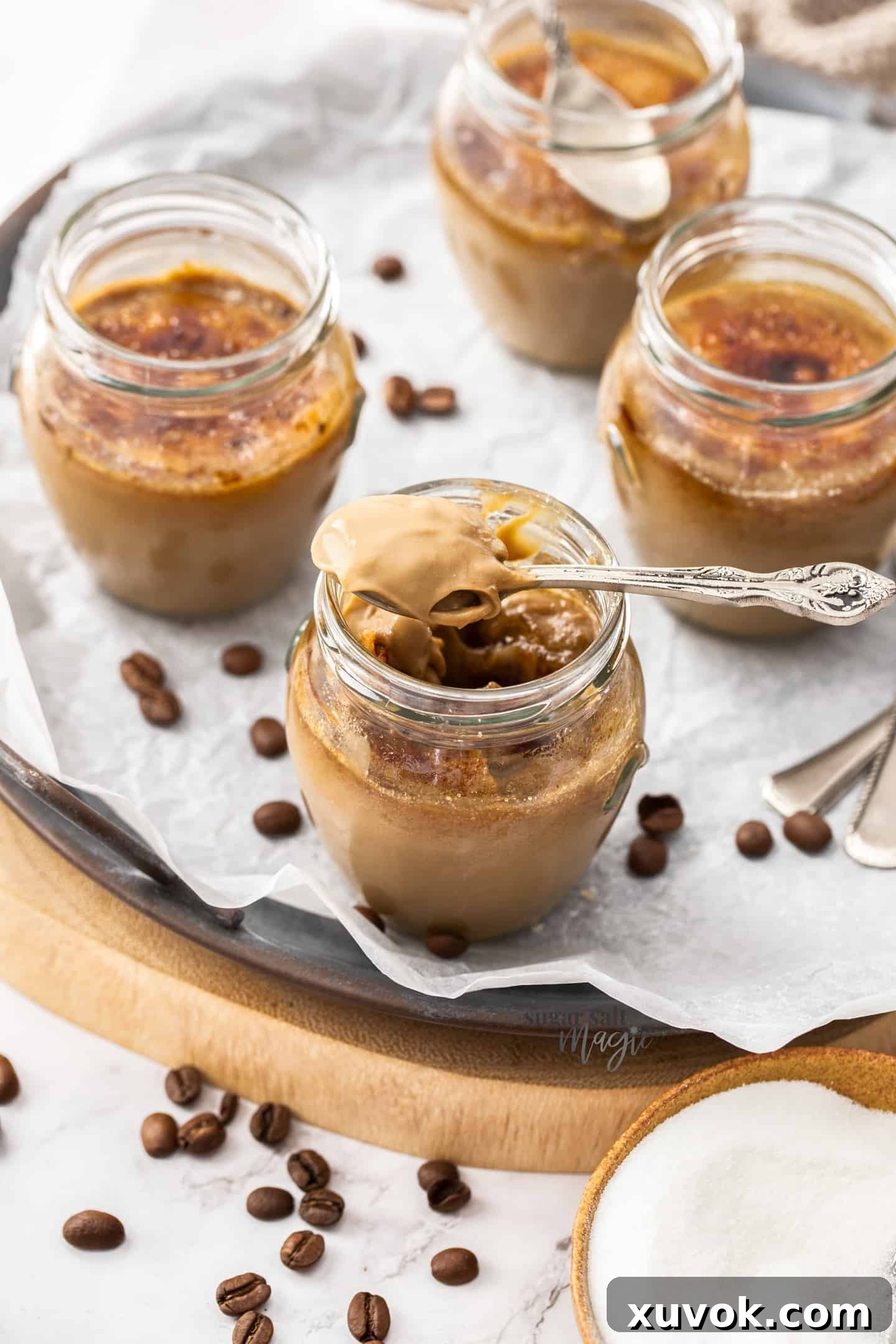 4 small glasses filled with coffee custard with a spoonful sitting on top.