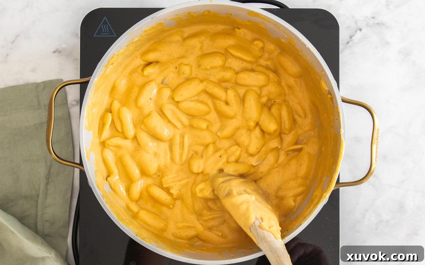 Stirring the pasta into the sauce.