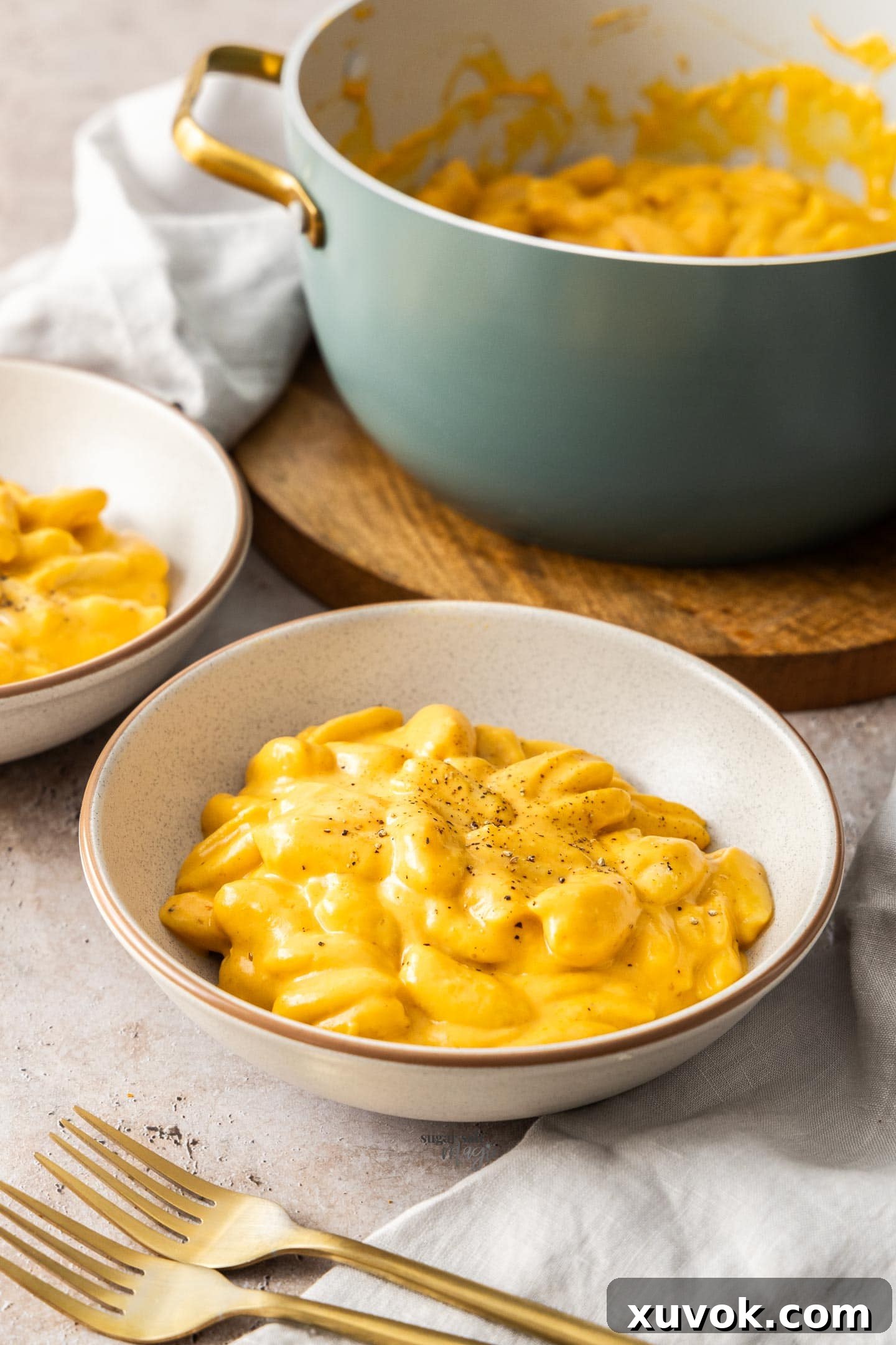 Two bowls of pumpkin mac and cheese with the pot in the background.