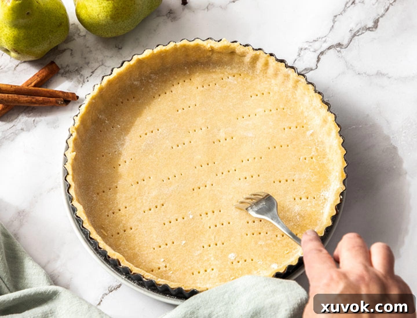 The base of the raw tart shell being pricked with a fork.