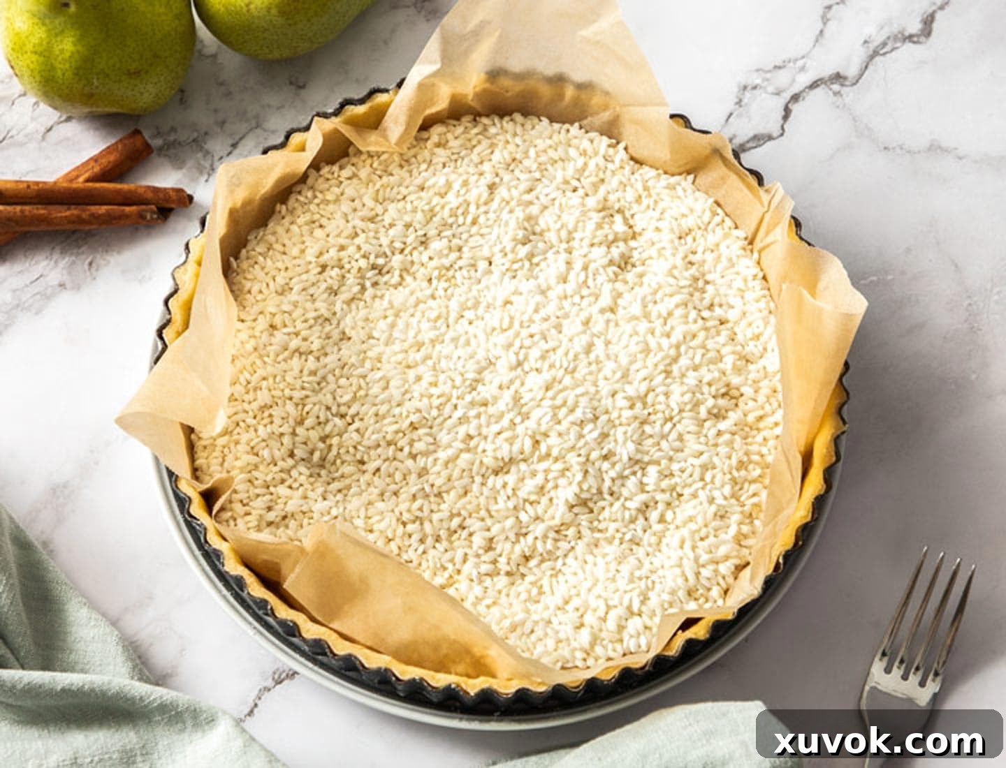 The tart shell filled with baking paper and rice.