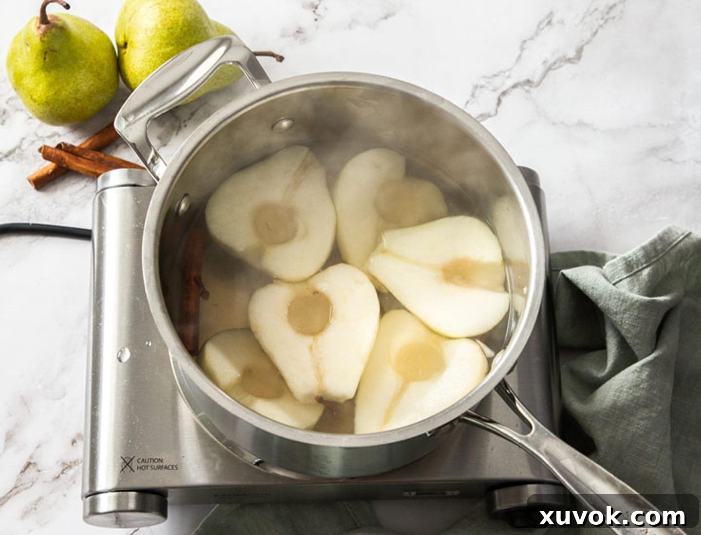 The pears poaching in a pan of water and spices.