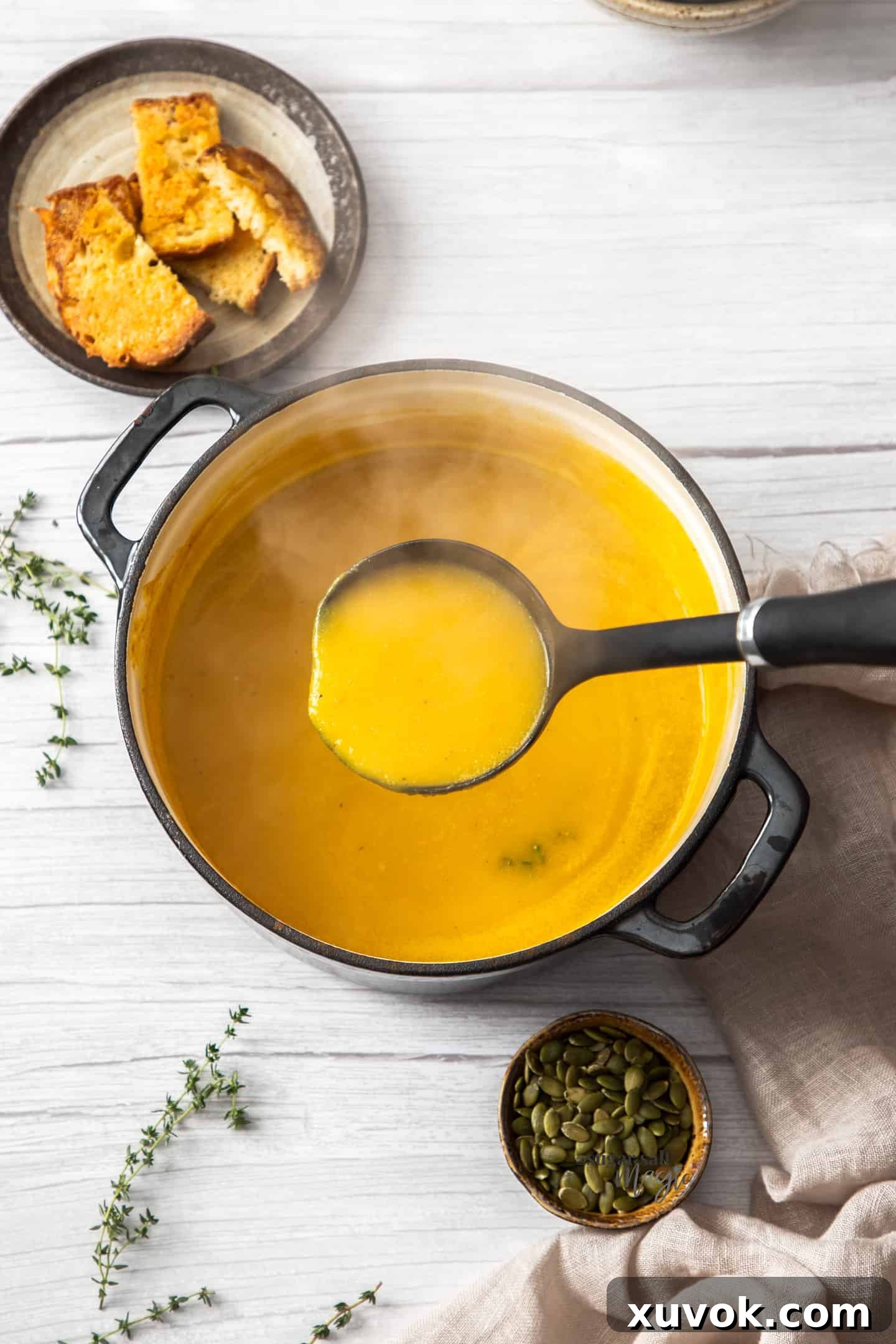 A rustic Dutch oven filled to the brim with creamy butternut squash soup, with a ladle poised to serve, evoking warmth and comfort.