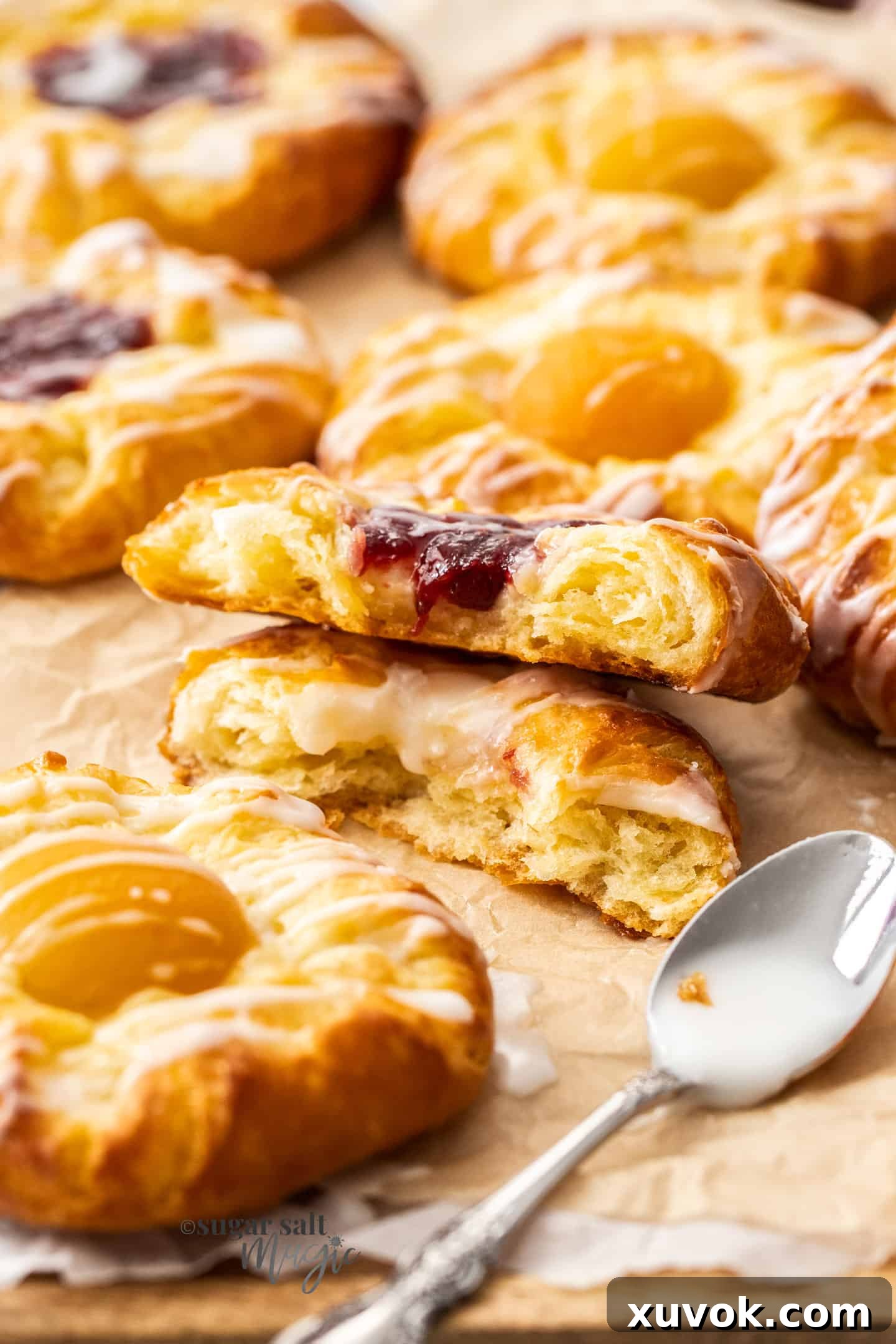 A perfectly baked custard danish, broken in half to reveal its flaky layers and creamy custard and jam filling, highlighting its exquisite texture.