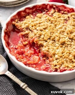 A white pie dish filled with baked strawberry crisp.