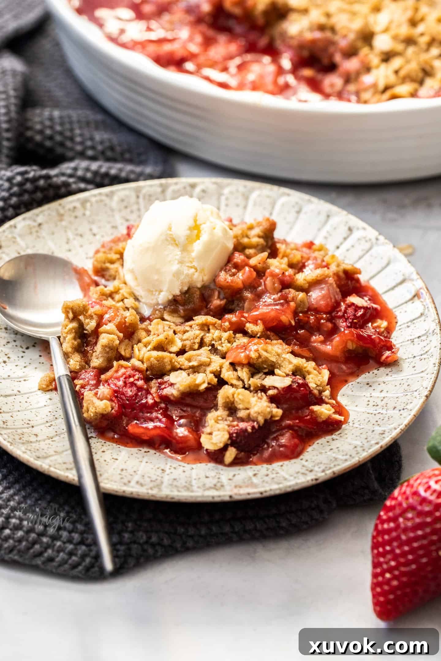 A plate filled with a generous serving of strawberry crisp topped with a scoop of vanilla ice cream.