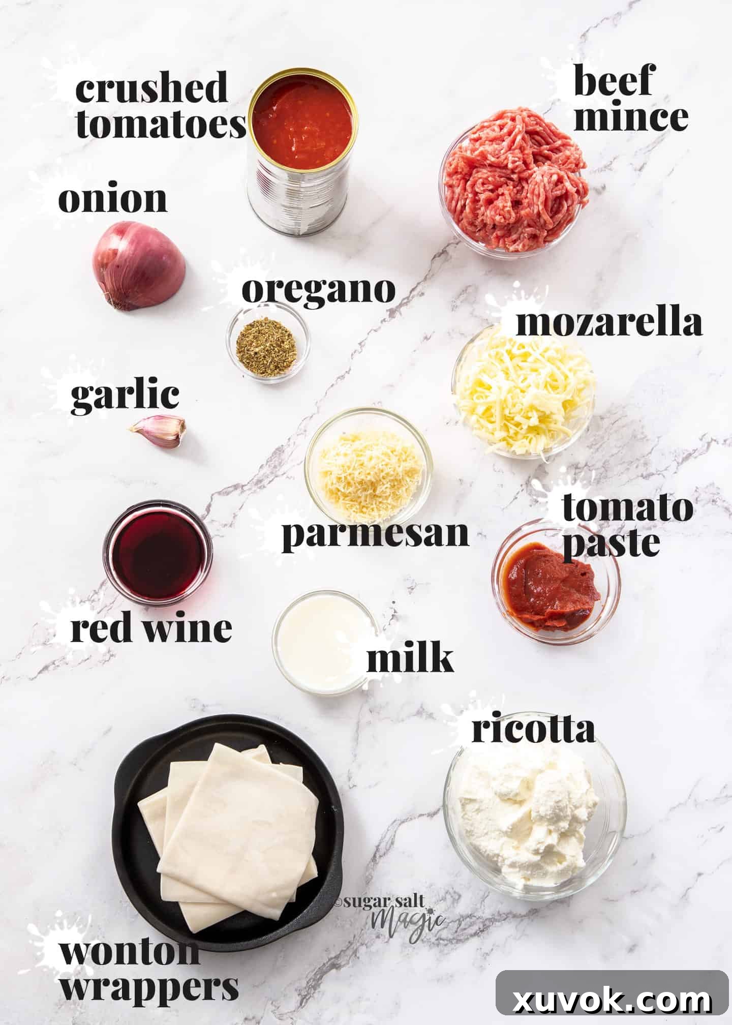 An array of fresh ingredients for lasagna cupcakes, including wonton wrappers, ground beef, tomatoes, cheese, and herbs, neatly arranged on a white marble countertop, ready for preparation.
