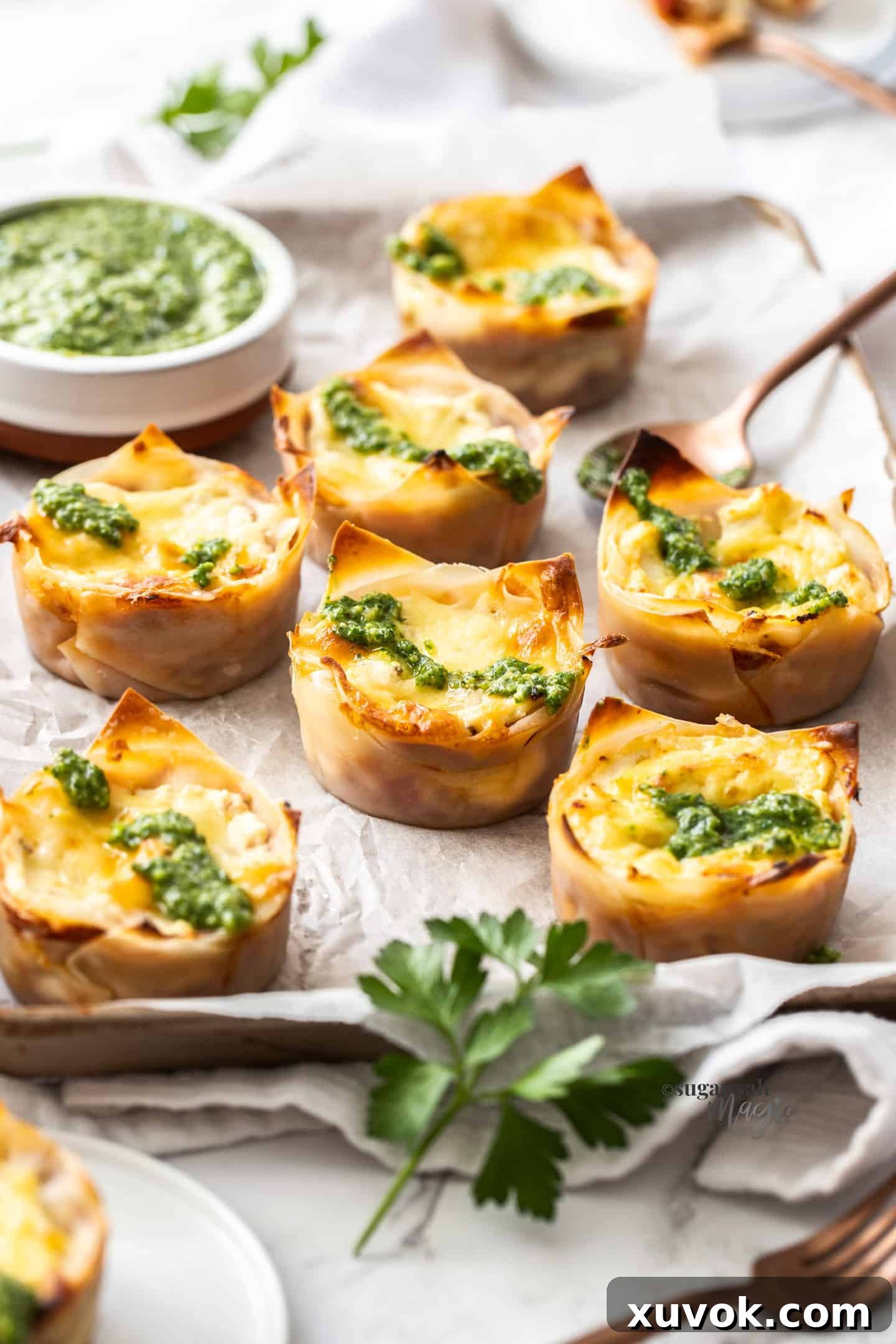 Seven perfectly baked lasagna cupcakes, golden and bubbly, sitting on a baking paper-lined tray, ready to be served as an appealing snack or appetizer.