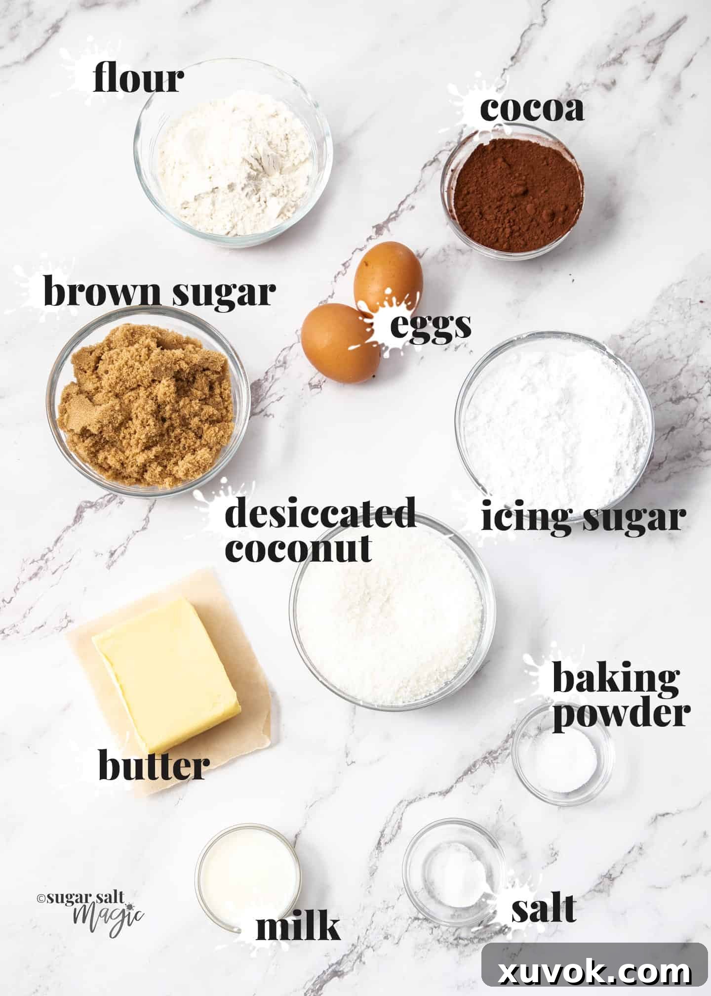 Various ingredients for a homemade chocolate coconut slice laid out on a marble surface, ready for baking.