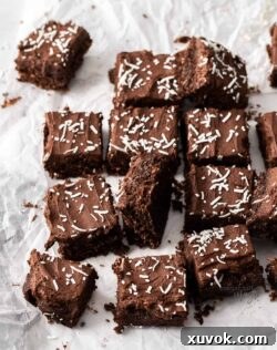 A batch of chocolate coconut slice on a crumpled sheet of baking paper, freshly baked and ready for frosting.