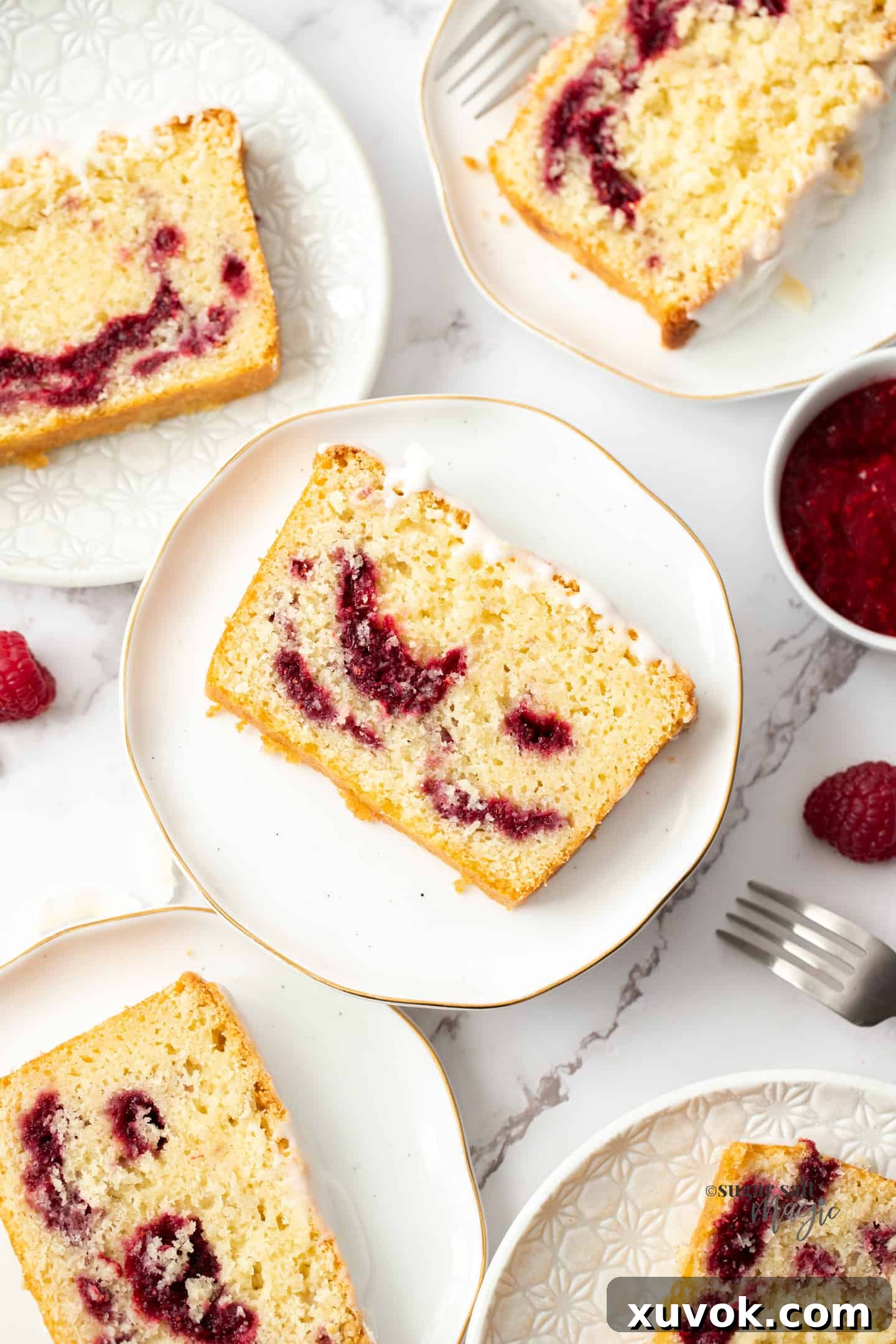 Top down view of 5 slices of moist coconut raspberry cake on white plates with a small bowl of raspberry compote next to it.