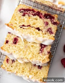Top down view of 3 generous slices of fluffy coconut raspberry cake adorned with white icing, neatly arranged on a rustic wire rack.
