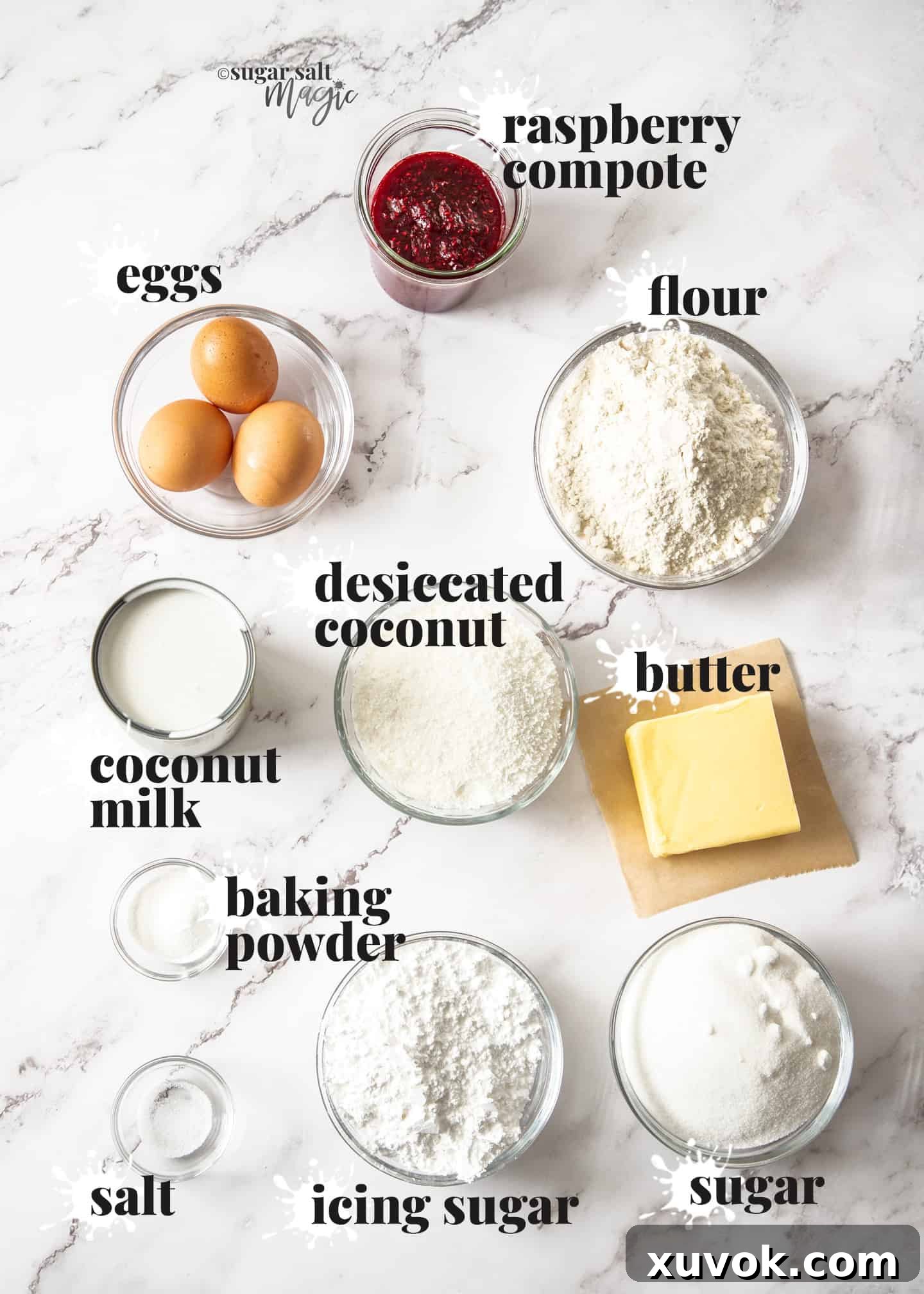 A collection of ingredients for coconut raspberry loaf cake artfully arranged on a sophisticated marble bench top, including fresh raspberries, coconut milk, butter, flour, and sugar.