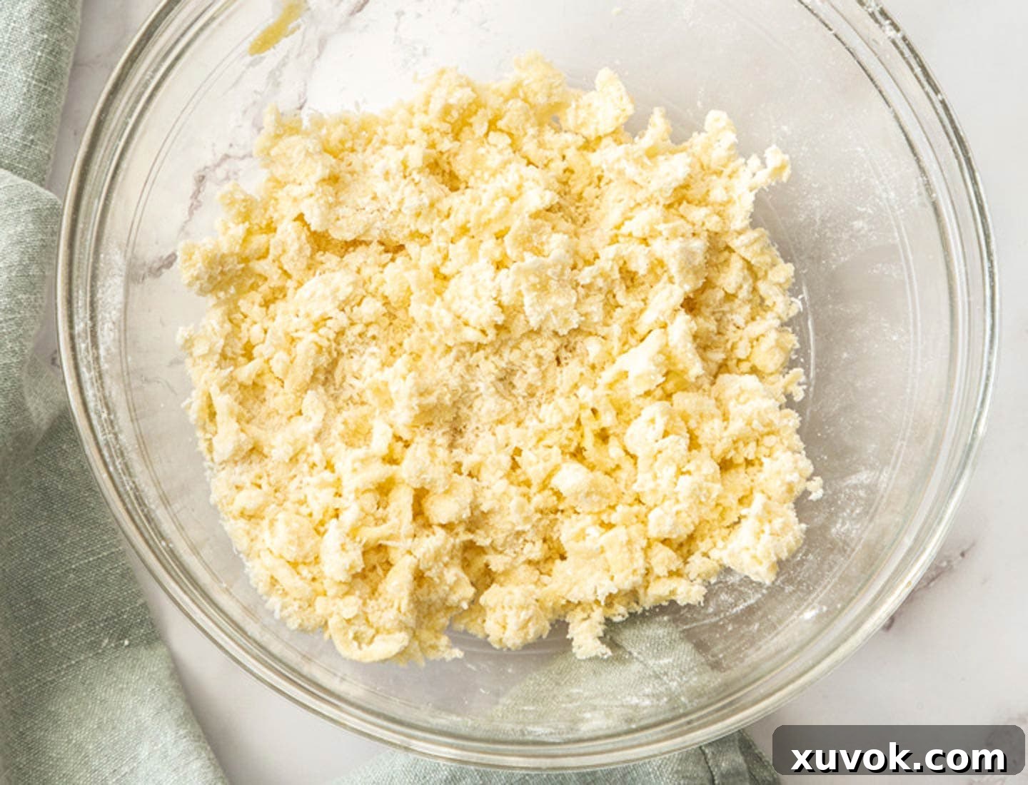 The perfectly combined crumble topping, featuring coconut and butter, resting in a clear glass bowl, ready for chilling.
