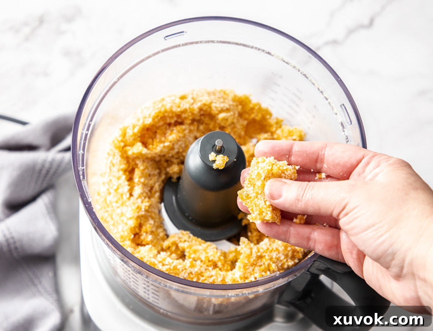 A hand holding a piece of the apricot bliss ball dough, demonstrating its perfect sticky, rollable texture.