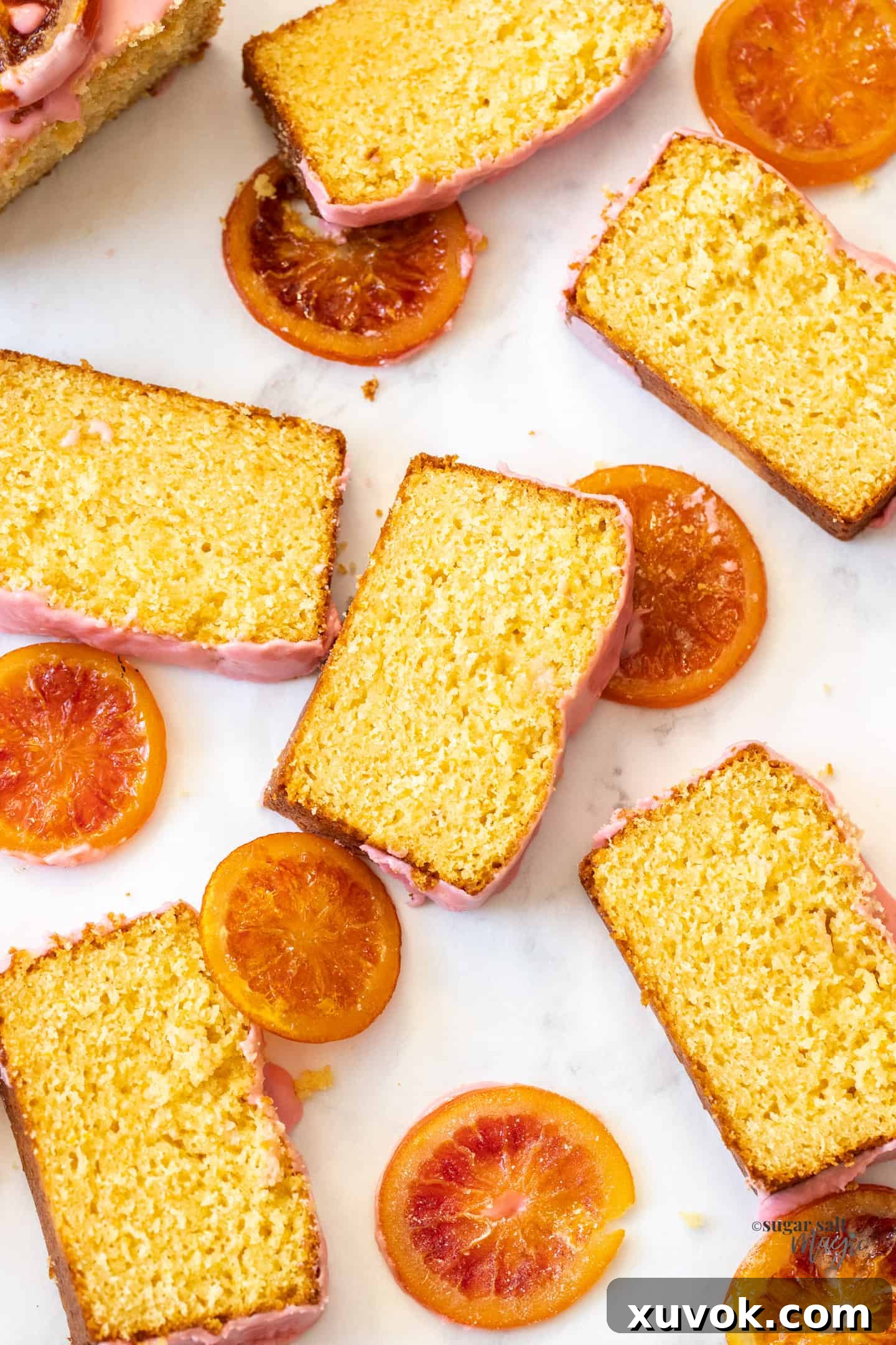Slices of orange loaf cake surrounded by candied oranges.