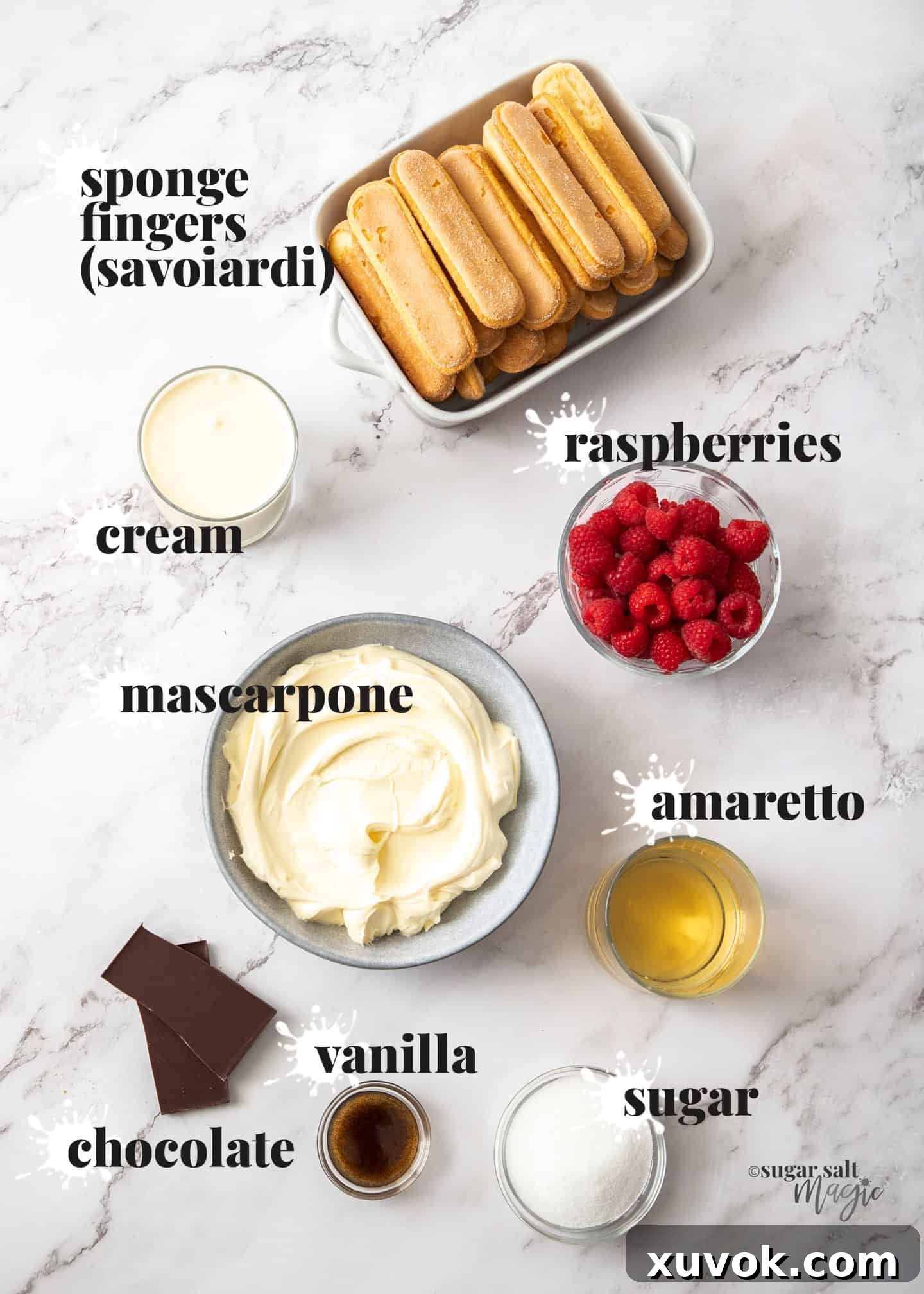 A beautifully arranged flat lay of all the fresh ingredients needed for raspberry tiramisu, displayed on a elegant marble background.