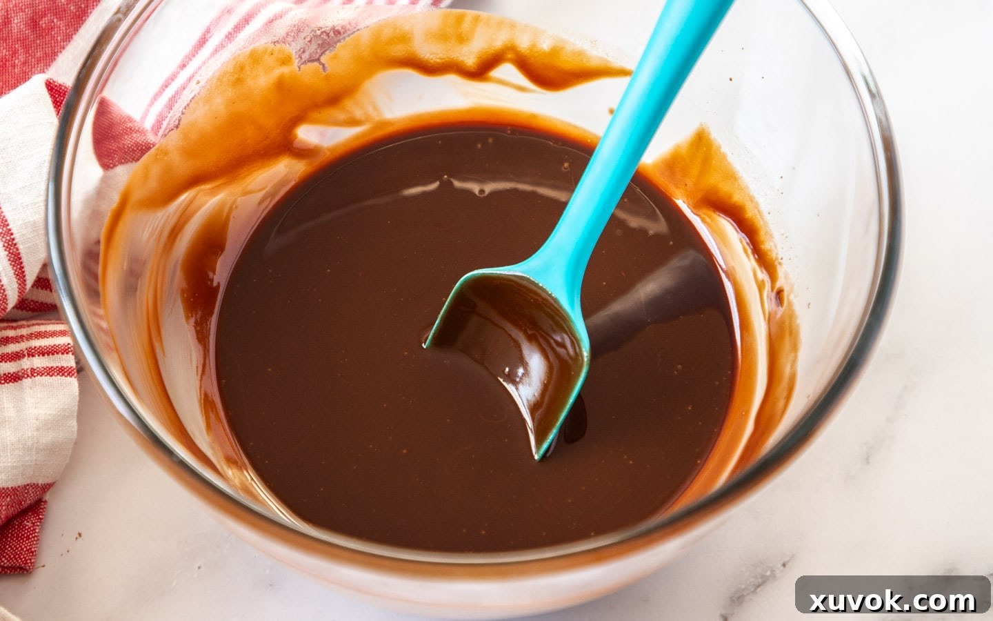 A smooth, glossy mixture of melted dark chocolate and unsalted butter in a heatproof bowl, ready to be incorporated into the brownie batter.