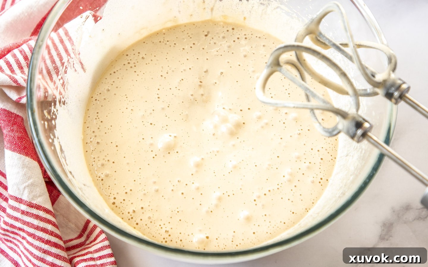 Eggs and both white and brown sugars beaten together in a large mixing bowl until the mixture is light, pale, and fluffy, indicating proper aeration.