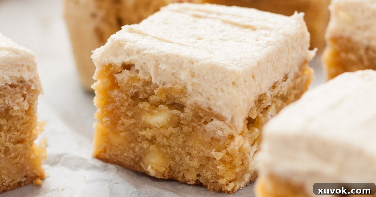 extreme closeup of a frosted blondie showing the inside texture and creamy frosting.