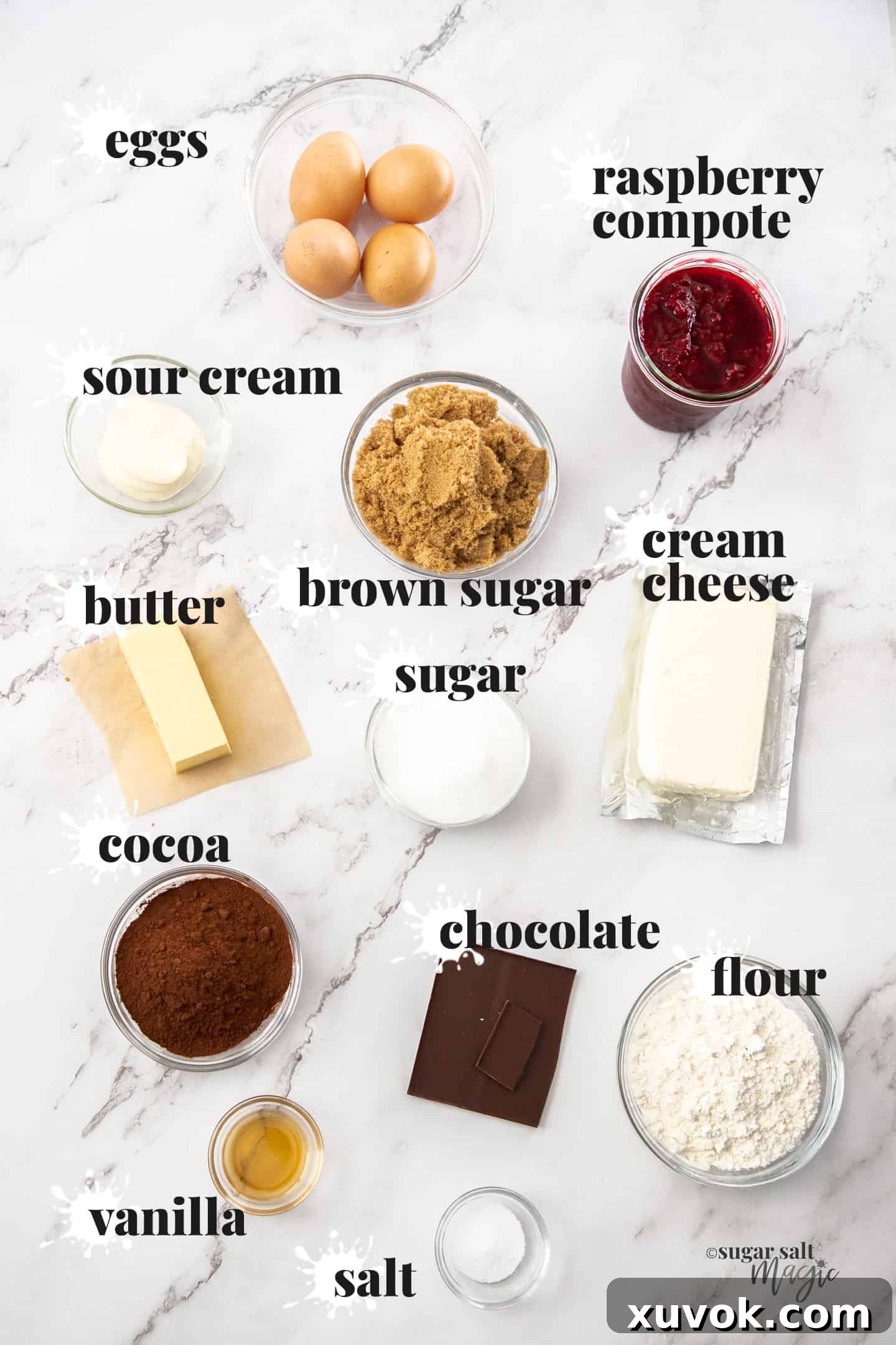 All the necessary ingredients for crafting raspberry cheesecake brownies, neatly arranged on a pristine marble countertop.