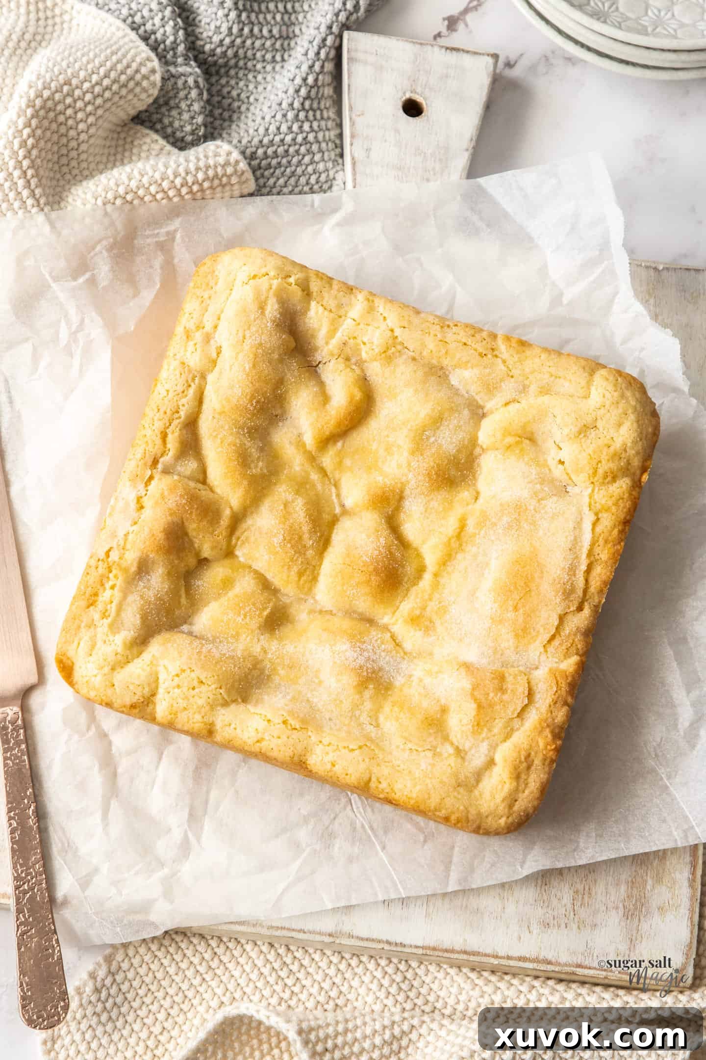 A stunning top-down view of a whole, freshly baked apple shortcake, beautifully golden and rustic, presented on a pristine white serving board.