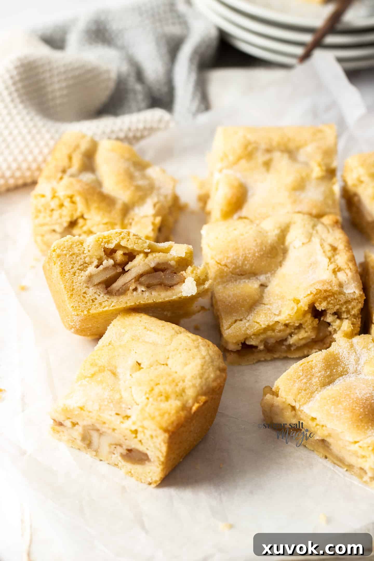 Individual slices of golden-brown apple shortcake resting on a sheet of baking paper, highlighting the delightful crumb and filling.