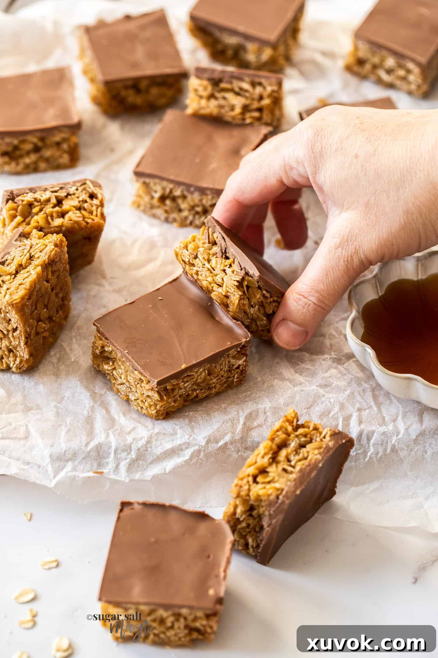 A hand reaching into a tray of freshly baked and set chocolate flapjacks, about to grab a delicious bar.