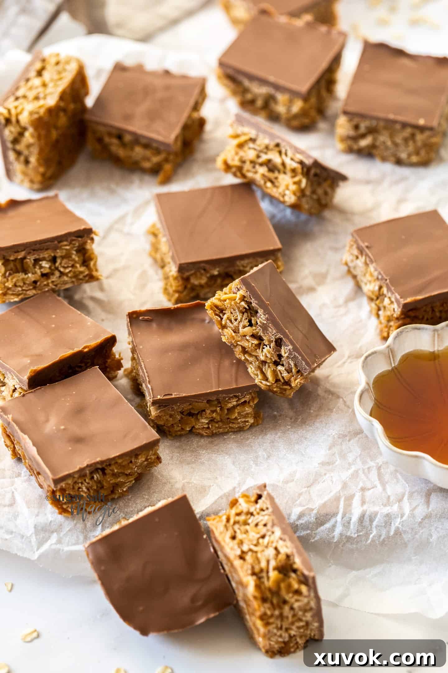 A generous batch of golden chocolate flapjacks, cut into perfect squares, resting on a sheet of baking paper ready to be enjoyed.