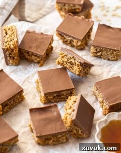 A batch of chocolate flapjacks, perfectly golden and topped with chocolate, on a sheet of baking paper.
