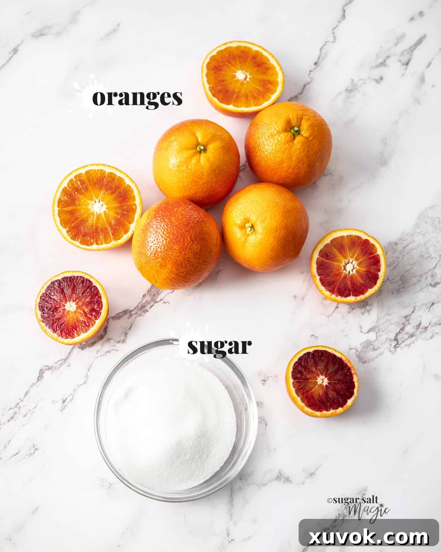 Fresh oranges and granulated white sugar are displayed on a pristine marble countertop, ready for making simple syrup.