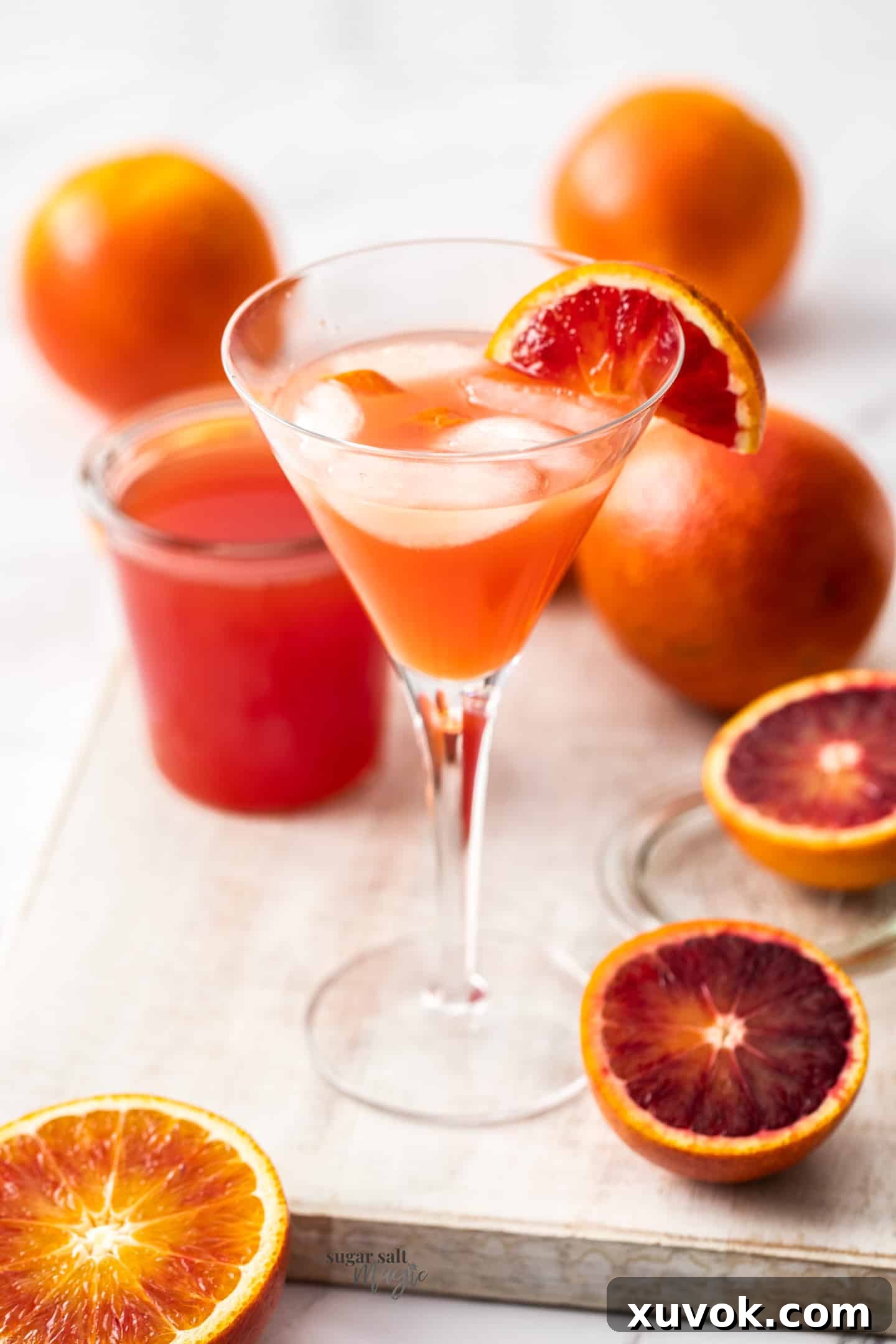 A elegant cocktail glass filled with a vibrant orange beverage, garnished with a fresh orange slice on the rim.