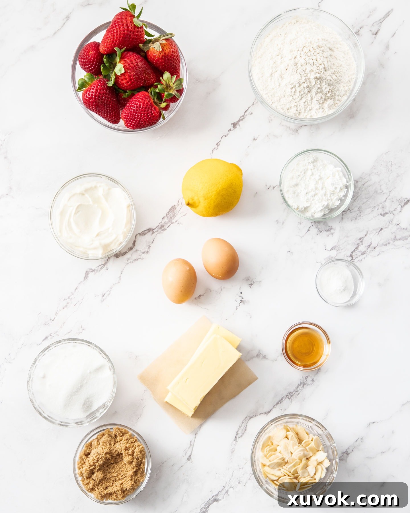 A selection of fresh ingredients laid out on a marble surface, ready for making strawberry crumb cake.