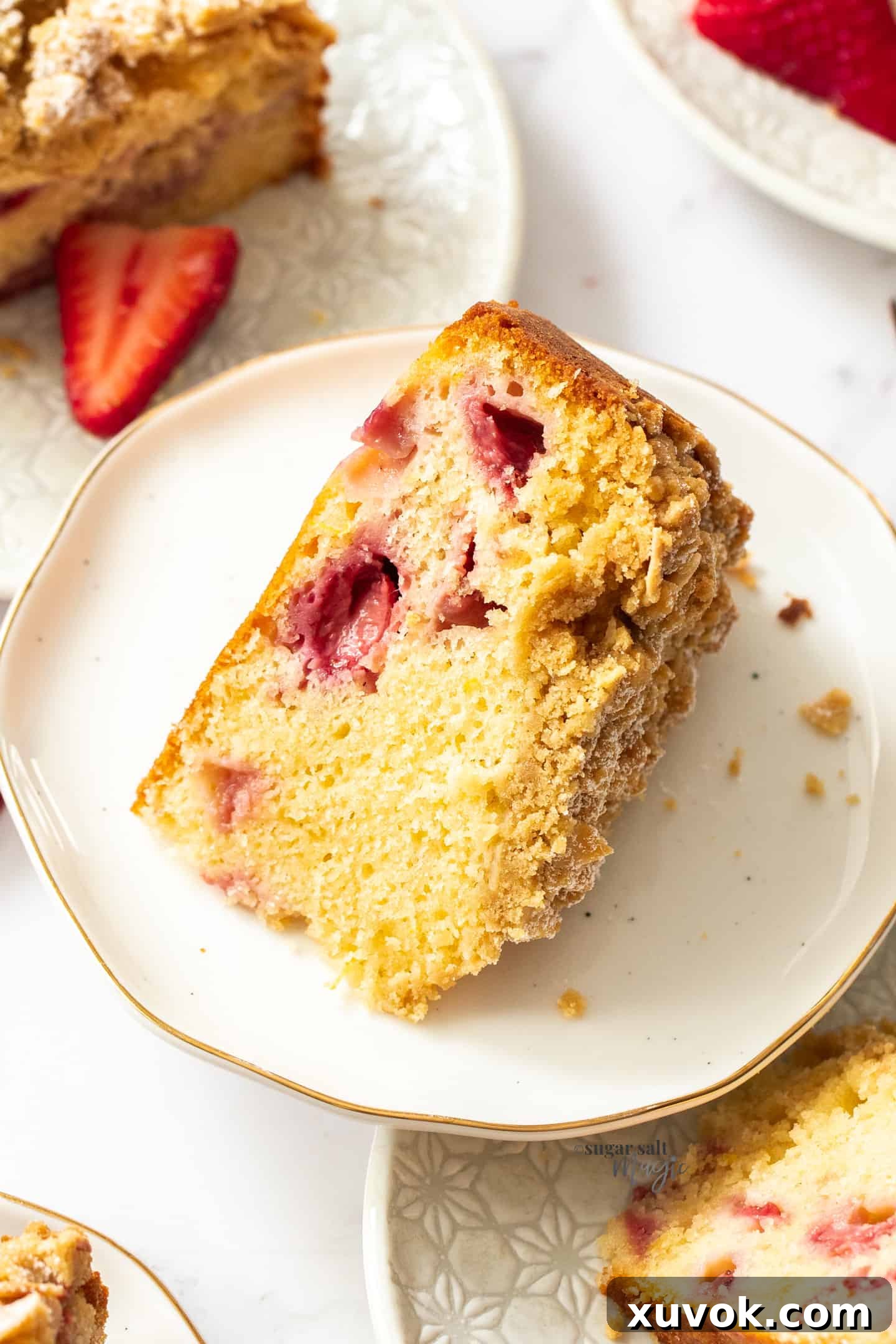Top down view of a delectable slice of strawberry crumb cake on a white plate, showcasing the fruit and crumb.