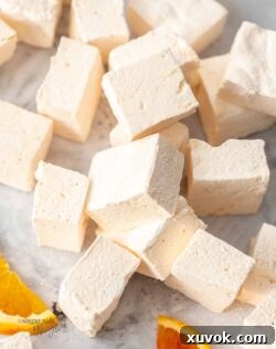 A pile of orange marshmallows on a grey marble surface.